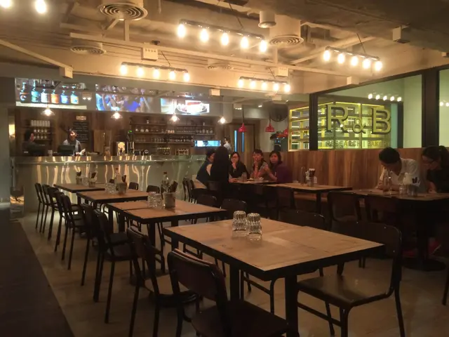 Spacious dining area with a few tables and chairs and a open kitchen in front of the dining area