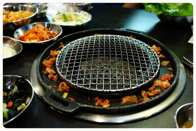 店員放入泡菜粒, 倒入蛋漿於爐邊慢慢煮熟, 這種食法新穎又有趣