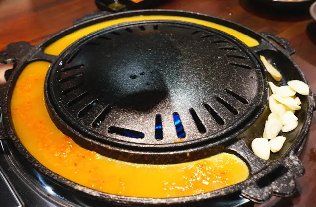 接著店員將蛋漿倒進爐邊, 兩邊用來烤爐邊蛋, 一邊用來烤蒜頭