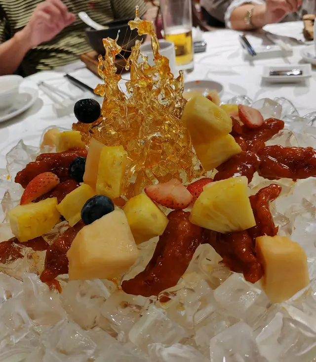 呢味餸先講擺設都相當震撼，中間擺設以拔絲製作出冰山，鋪滿新鮮嘅生果，咕嚕肉選用五花腩作食材，再用咕嚕汁緊緊包在外層，以冰鎮既方法處理，令表面非常卜卜趣。
