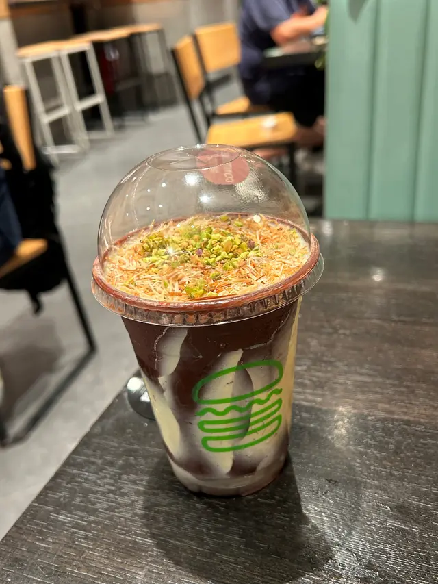 杜拜飛來嘅神級奶昔！黑朱古力脆皮超好玩，雲呢拿雪糕配意大利開心果絲滑香濃，酥皮絲加分，層次爆棚！😋每啖都充滿住椰香酥皮絲同開心果。完美平衡開心果奶昔嘅絲滑同配料嘅酥脆